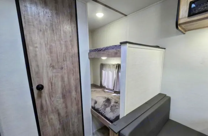 Cozy RV rental interior featuring modern bunk beds, a stylish textured door, and comfortable seating.. Gulf Stream Kingsport Lite 199DD 2025