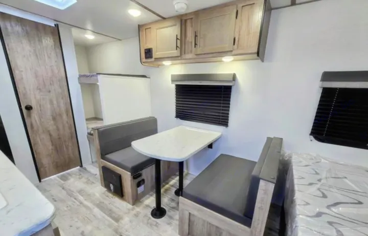 RV rental interior: This image shows a dinette with benches, overhead cabinets, and bunk beds in a cozy space.. Gulf Stream Kingsport Lite 199DD 2025
