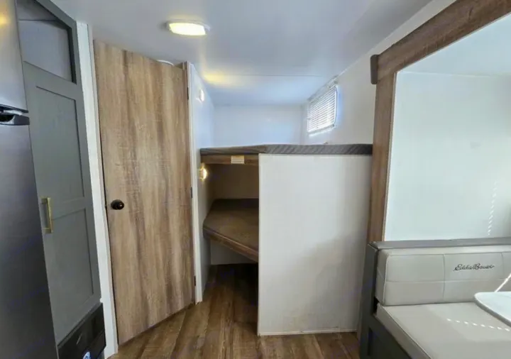 Bright RV rental interior with a bunkhouse, light wood-look floor, and a comfy dinette.. Heartland RVs Eddie Bauer EBS 261BH 2024
