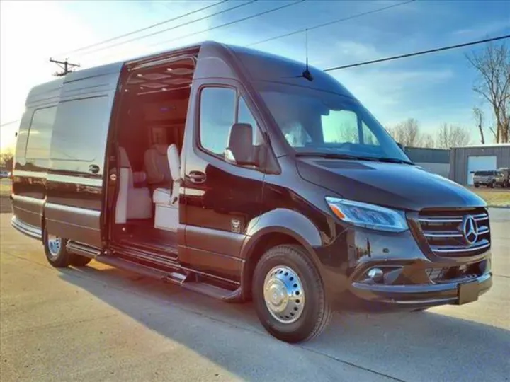 Black Mercedes-Benz Sprinter luxury van, an ideal RV rental, with open side door revealing its plush interior.. Mercedes-Benz Sprinter 2025