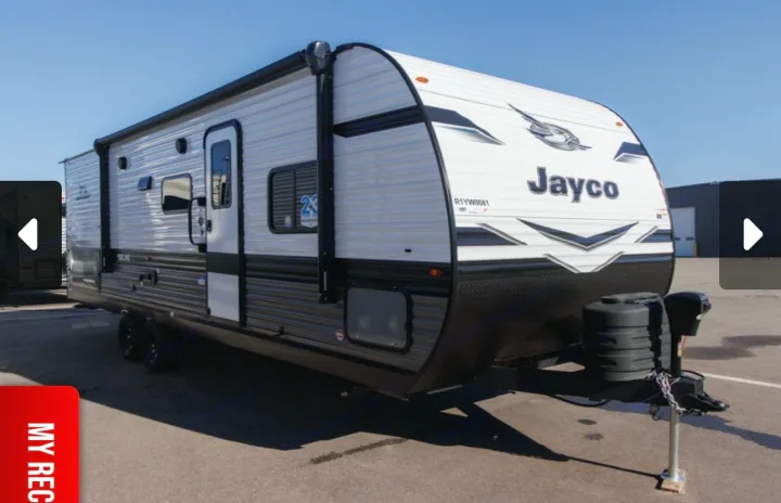 New Jayco travel trailer for rv rental. White with black trim, awning, and windows, parked outdoors. Perfect for a road trip adventure.. Jayco Jay Flight SLX 2025