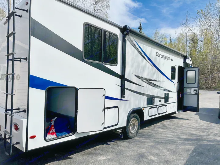 White Forest River Sunseeker RV rental, parked outdoors. Open storage bays, rear ladder. Perfect for travel & camping adventures.. Forest River Sunseeker LE 2021