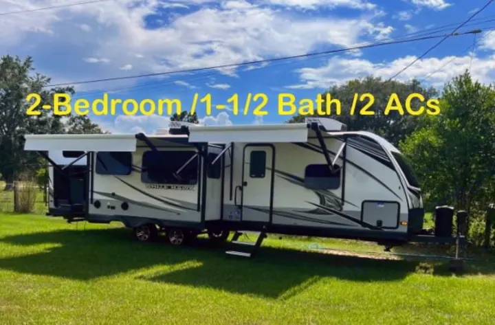 RV rental: 2-Bedroom, 1-1/2 Bath travel trailer with 2 ACs, parked on green grass under a blue sky.. Jayco White Hawk 2022