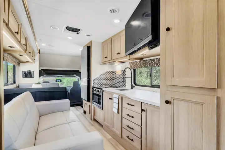 Bright, modern RV rental interior featuring a full kitchen, living area, and dinette. Ideal for your travel adventures.. Forest River Sunseeker 2550 DSLE 2025
