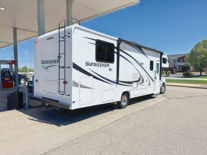A white Sunseeker motorhome rv rental is seen fueling up at a Citgo gas station under a clear blue sky.. Forest River Sunseeker LE 2019