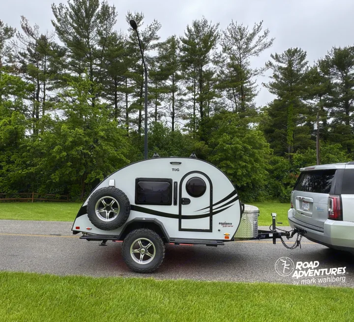 Silver SUV towing a T@G Boondock Black Canyon teardrop camper. Perfect for your next rv rental adventure!. nuCamp T@G XL 2025