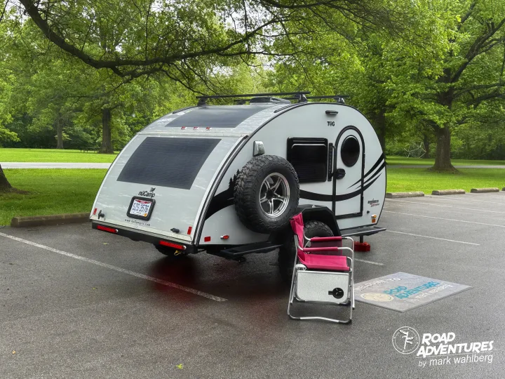 A nuCamp T@G teardrop camper, perfect for an rv rental adventure, parked in a lush park with a pink chair and mat.. nuCamp T@G XL 2025