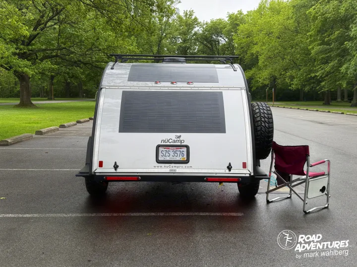 Rear of a white nuCamp teardrop trailer with solar panels and a spare tire, parked for a likely rv rental adventure.. nuCamp T@G XL 2025
