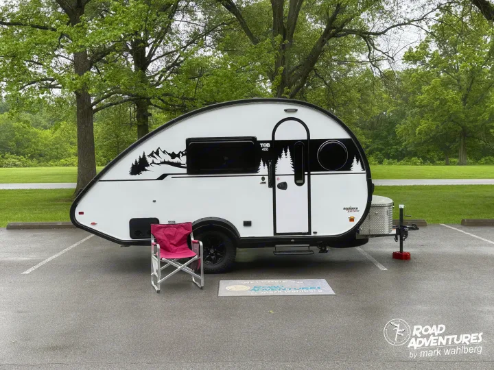 A white T@B 400 teardrop trailer RV rental with mountain graphics, ready for your next outdoor adventure or camping trip.. nuCamp T@B 2025