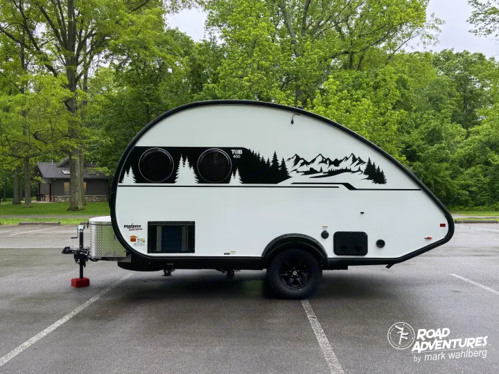 This white T@B 400 Boondock teardrop rv rental, adorned with mountain decals, awaits your next camping adventure in nature.. nuCamp T@B 2025