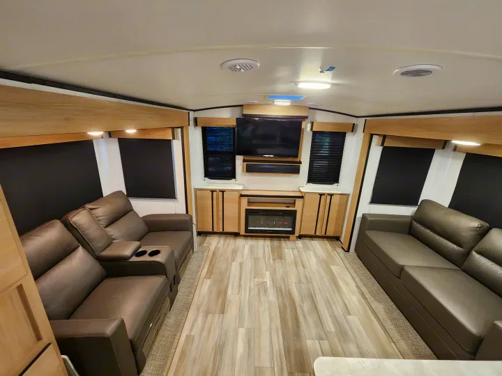 Modern RV rental living space with dual recliners, entertainment center, and fireplace for comfortable travel.. Cruiser RV Radiance 2022