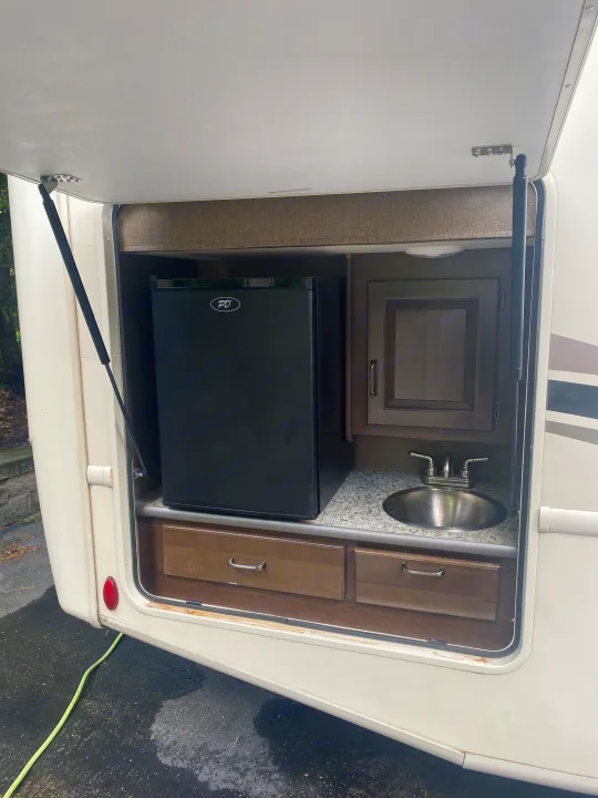 RV rental's outdoor kitchen features a mini-fridge, sink, and storage drawers for easy use.. Thor Hurricane 2018