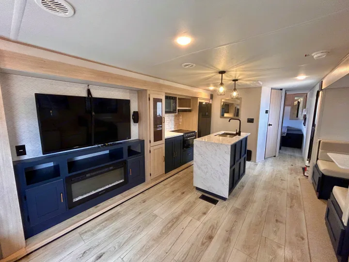 Experience comfort in this modern RV rental's living and kitchen space, featuring TV, fireplace & island.. Primetime Avenger 2025