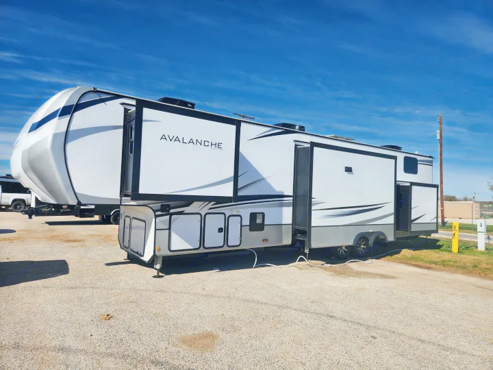 Spacious Keystone Avalanche fifth-wheel RV rental, perfect for road trips & camping, shown fully extended on gravel.. Keystone RV Avalanche 2023