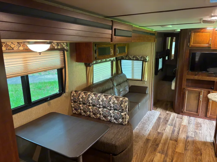 Functional RV rental interior showcasing a dinette, sofa, windows, and overhead cabinets for a comfortable journey.. Keystone RV Outback Ultra-Lite 2017