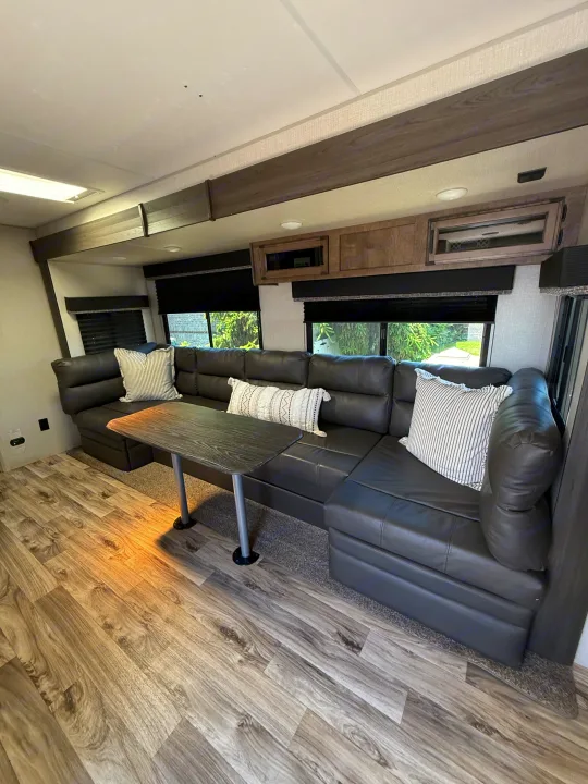Enjoy this RV rental's inviting living space with a large leather sectional, dining table, and modern wood-look floor.. Sport Trek 270 VBH 2021
