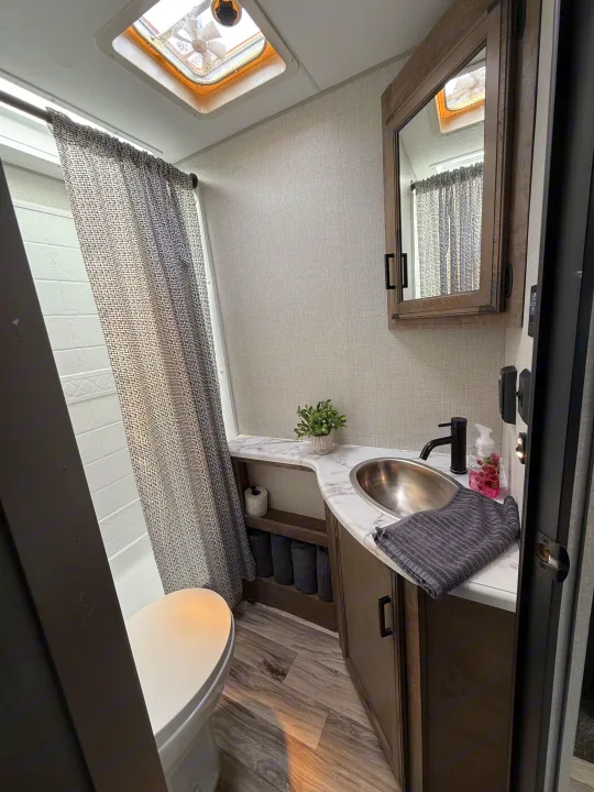 Bright and compact RV rental bathroom with a shower, toilet, and vanity sink area.. Sport Trek 270 VBH 2021