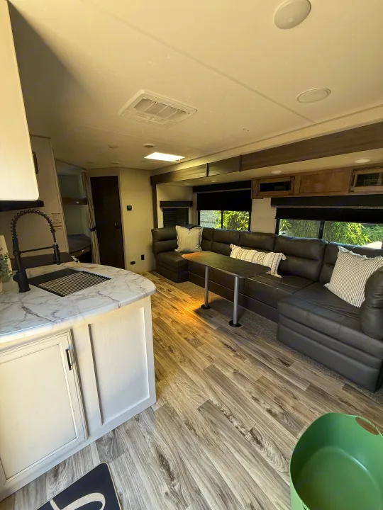 Modern rv rental interior: spacious living area with kitchen, large sofa, and wood flooring.. Sport Trek 270 VBH 2021