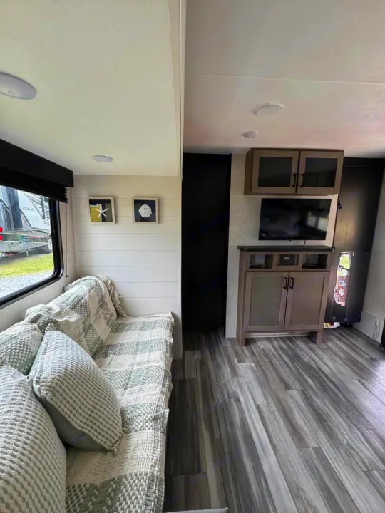 RV rental interior: inviting living area with patterned sofa, shiplap wall decor, and a media console with TV.. Jayco JAY Flight SLX 261BHS 2025