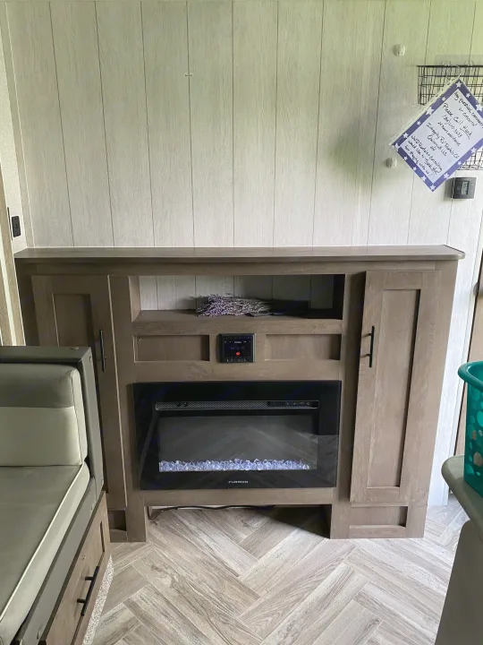 Cozy RV rental living area featuring a modern electric fireplace and entertainment unit.. Forest River Wildwood X-Lite 2022