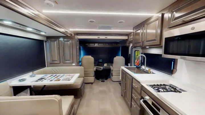 Modern RV rental interior: a full kitchen, dining area, driver's cockpit, and overhead bunk in neutral tones.. Georgetown GT7 2022