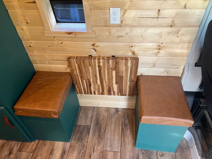 RV rental: Custom wood interior with teal storage benches, brown cushions, and a versatile wooden table, perfect for van life comfort.. Dodge ProMaster 2500 2018
