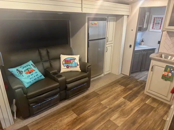 Comfortable RV rental living area featuring reclining seats, refrigerator, and camper-themed decor.. Keystone RV Cougar 2022