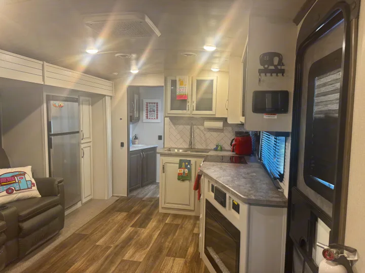 Modern RV rental interior featuring a well-equipped kitchen, comfortable seating, and a fireplace. Explore in style!. Keystone RV Cougar 2022
