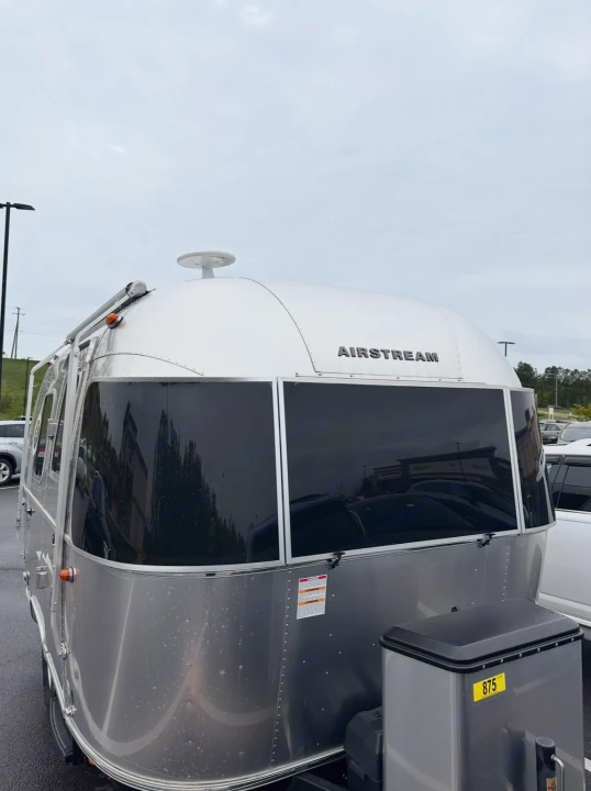 A classic silver Airstream rv rental travel trailer, with dark windows, parked under an overcast sky.. Airstream Bambi 2022