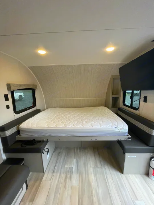 Modern RV rental interior featuring a comfortable bed, dual seating benches, and a wall-mounted TV.. Forest River Coachmen Clipper 2024