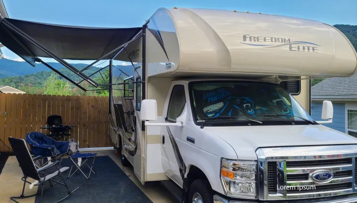 This RV rental, a Freedom Elite model, is parked with its awning extended, featuring chairs, a grill, and mountain views.. Thor Freedom Elite 2019