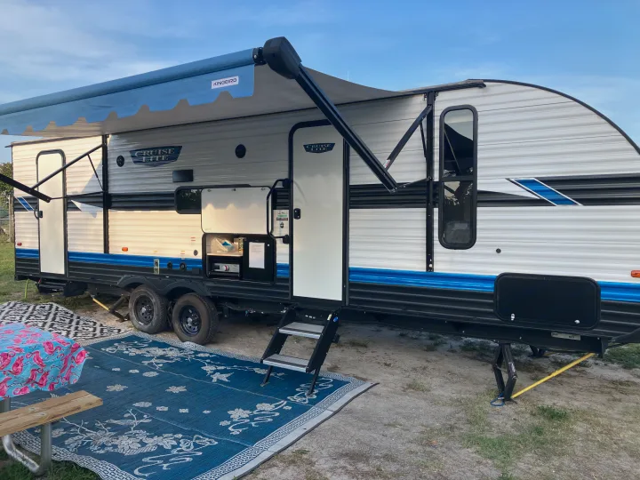 Spacious rv rental setup with extended awning, outdoor mats, and picnic area, ready for camping adventures.. Forest River Salem Cruise Lite 2023