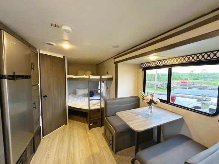 This RV rental features a practical interior with a dining area, bunk beds, and a refrigerator. Ideal for travel.. Forest River Grand River Comfortline 2021