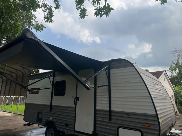 A modern grey & white travel trailer with extended awning, ideal for your next RV rental adventure.. Coleman Lantern 17B 2024