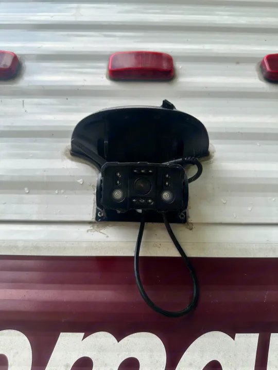 RV rental backup camera mounted on white ribbed siding, with two red lights above. Essential for safe reversing.. Coleman Lantern 17B 2024