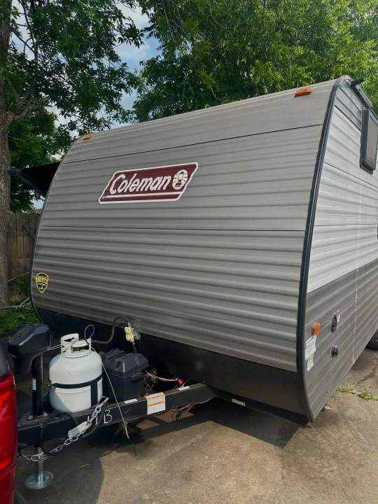 Front view of a grey Coleman travel trailer, ideal for rv rental, showing the hitch, propane tanks, and battery box.. Coleman Lantern 17B 2024