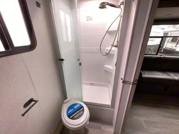 Explore this RV rental's compact bathroom, featuring a toilet, shower, and functional design for travel.. Winnebago Voyage 2022