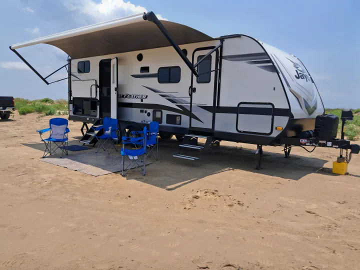 Experience beach camping with this comfortable rv rental travel trailer. Awning out, chairs ready on the sand.. Jayco Jay Feather 2022