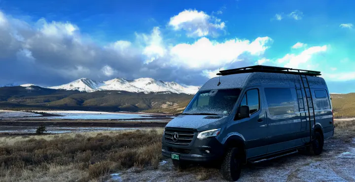 This stunning Mercedes Sprinter rv rental is ready for adventure in a snowy mountain landscape, with a lake under a bright blue sky.. Mercedes-Benz Sprinter 2021