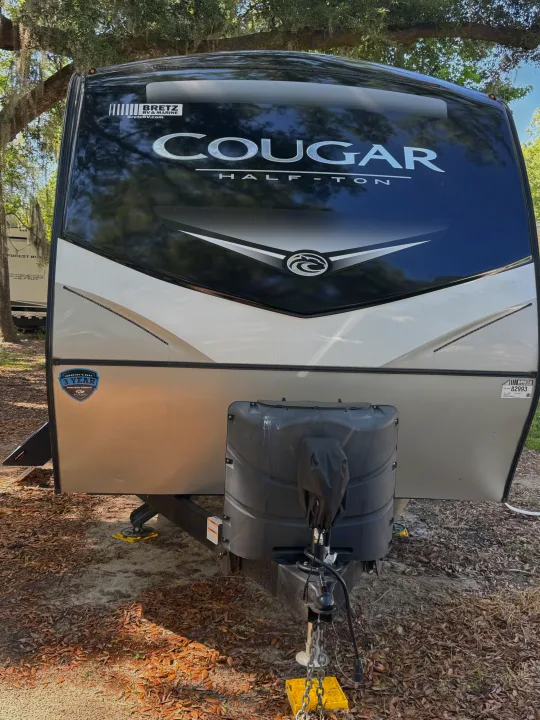 Front view of a white and black Cougar travel trailer, ready for your next RV rental adventure or camping trip.. Keystone RV Cougar 2022