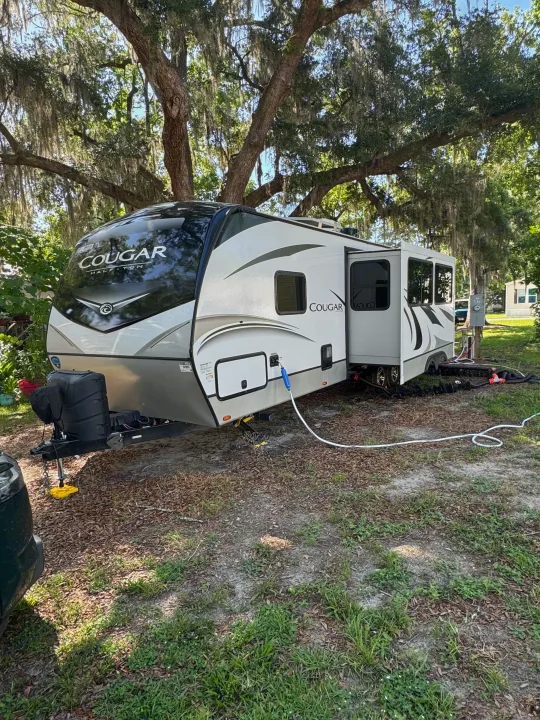 Enjoying nature! This spacious Cougar travel trailer RV rental is fully set up at a shady campsite under mossy trees.. Keystone RV Cougar 2022