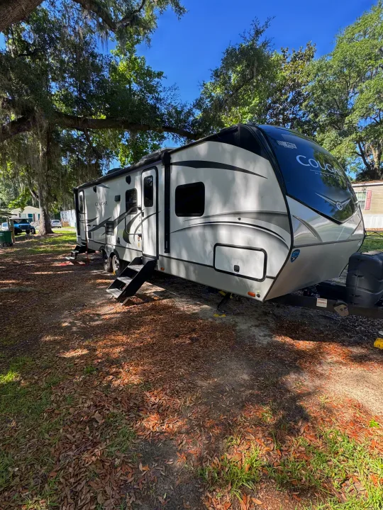 Spacious RV rental ready for adventure, parked among mossy trees in a sunny park setting.. Keystone RV Cougar 2022