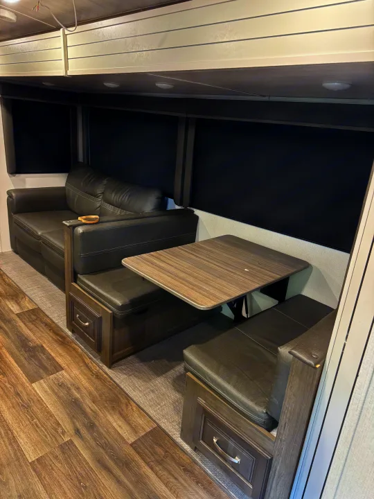 RV rental interior showing a dark gray sofa, dinette with table, and overhead cabinets.. Keystone RV Cougar 2022