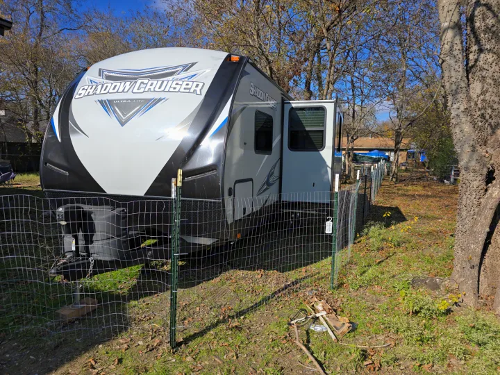 Shadow Cruiser Ultra-Lite travel trailer RV rental, parked in a treed yard behind a wire fence, door open.. Cruiser RV Shadow Cruiser 2019