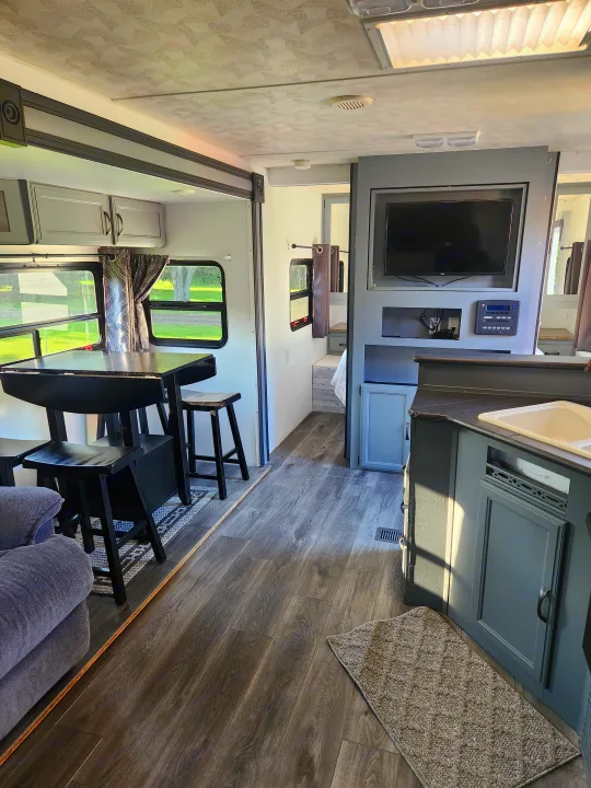 This RV rental interior features a gray kitchen, dining table, and living area with wood-look floors.. Forest River Palomino Puma 2013