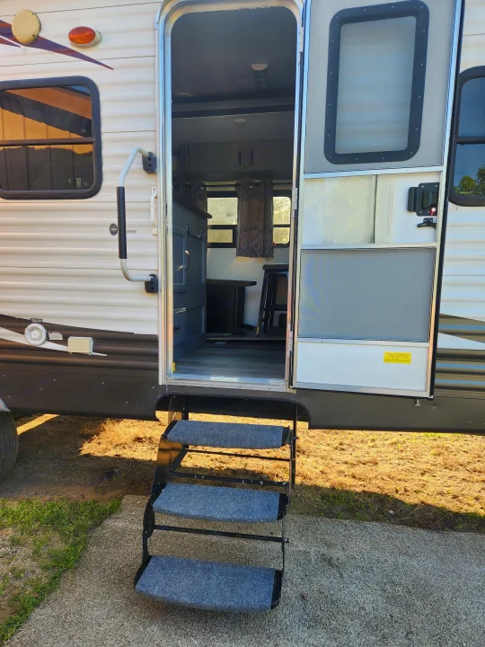 Open RV rental door with grey carpeted steps leading to a functional interior, ready for your next adventure.. Forest River Palomino Puma 2013