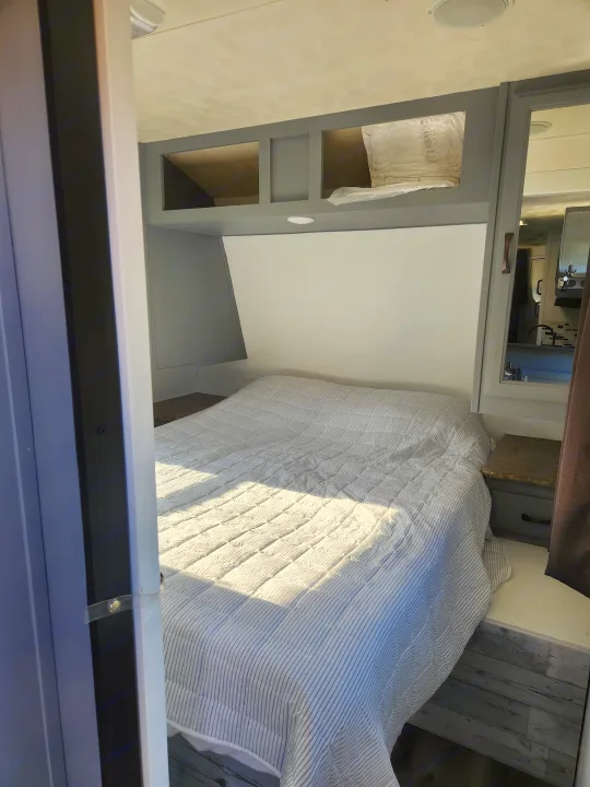 Step inside this cozy RV rental bedroom, featuring a comfortable bed, overhead storage, and bright, modern interior design.. Forest River Palomino Puma 2013