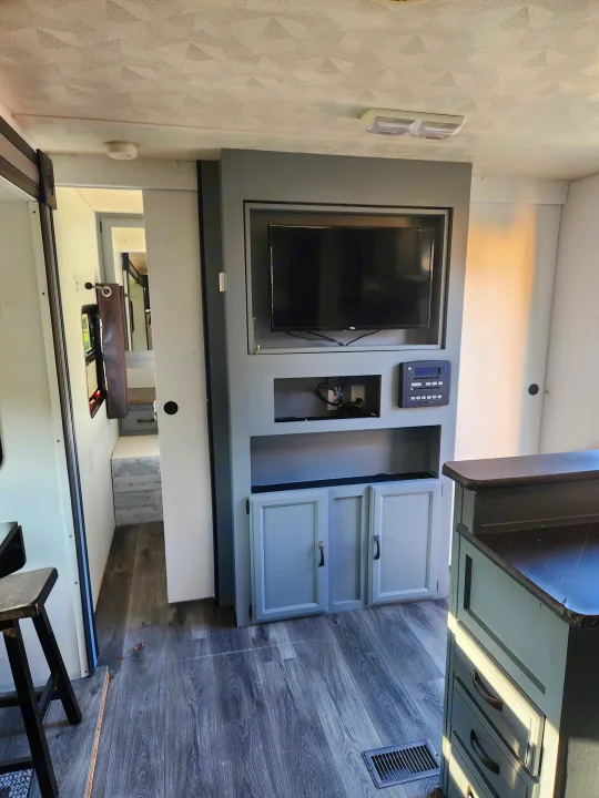 Tour this inviting rv rental interior, showcasing gray wood-look floors, entertainment center with TV, control panel, and renovated cabinets.. Forest River Palomino Puma 2013