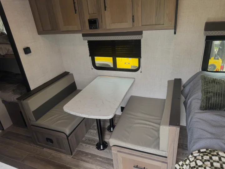 Bright RV rental dinette area with a table, comfortable benches, overhead storage, and bunks visible.. Gulf Stream Ameri-Lite Super Lite 2022