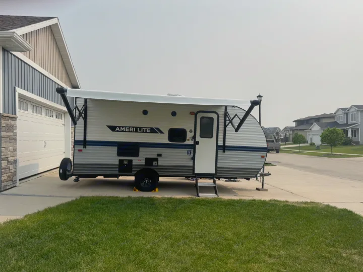 RV rental: An Ameri Lite travel trailer parked in a driveway with its awning extended at a suburban home.. Gulf Stream Ameri-Lite Super Lite 2022